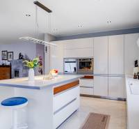 Családi ház konyhája szigettel, lámpával, beépített sütővel és kiegészítőkkel.