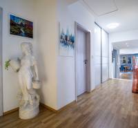 Egy családi ház folyosója fa dekor padlóval, dekoratív szoborral és képekkel a falakon.