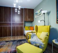 Szoba kényelmes fotellel, szekrénnyel, csillárral és fa dekorációjú padlóval egy családi házban.