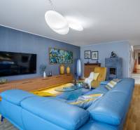 Nappali egy családi házban kék kanapéval, fa dekoros padlóval és televízióval.