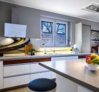 Konyha családi házban stílusos munkalappal, fehér szekrényekkel és dekorációkkal az ablakon.