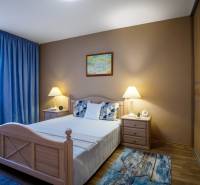 Hálószoba családi házban ággyal, éjjeliszekrényekkel és fa dekorációjú padlóval.