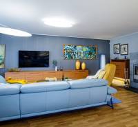 Nappali egy családi házban kandallóval, kanapéval és fa dekorációjú padlóval.