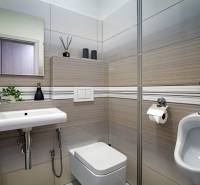 Fürdőszoba családi házban mosdóval, WC-vel és semleges tónusú csempével.