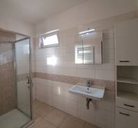 Fürdőszoba zuhanyzóval, mosdóval és csempével egy 4 szobás lakásban.