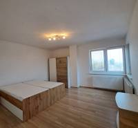 Hálószoba egy 4 szobás lakásban, fa mintázatú padlóval, ággyal és szekrénnyel.