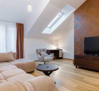 Világos nappali egy egyszobás lakásban, fa hatású padlóval és tetőablakkal.