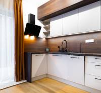 Konyha egy egyszobás lakásban fa mintás padlóval, függönnyel és modern készülékekkel.