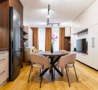 Egy szobás lakás belső tere fa dekorációjú padlóval, konyhával és étkezőasztallal.