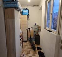 Keskeny folyosó egy családi házban polcokkal, ablakkal, elektromos rollerrel és cipőkkel.