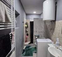 Fürdőszoba családi házban mosdóval, mosógéppel, bojlerrel és zuhanyzóval.