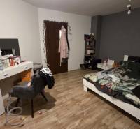 Hálószoba ággyal, íróasztallal és fa dekoros padlóval egy családi házban.