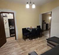 Nappali egy családi házban, fa mintázatú padlóval, asztallal és kanapéval.