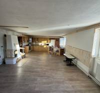 Családi ház belső tere konyhasarokkal, téglából épített kemencével és fa dekorációjú padlóval.