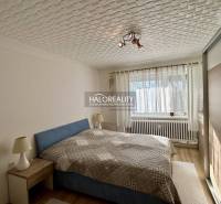 Világos hálószoba mennyezeti lámpával és fa dekorációjú padlóval egy kétszobás lakásban.