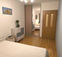 Hálószoba egy kétszobás lakásban fa dekor padlóval, tükrös szekrényekkel és képpel.