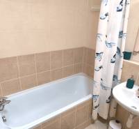 Fürdőszoba egy kétszobás lakásban káddal és semleges árnyalatú csempékkel.