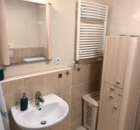 Fürdőszoba egy kétszobás lakásban mosdóval, szekrénnyel és törölközőszárító radiátorral.