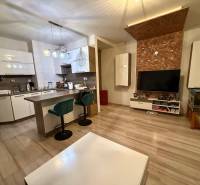 Nappali konyhával, bárpulttal és fa dekorációjú padlóval egy kétszobás lakásban.