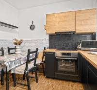 Konyha fa dekorációval, étkezőasztallal és háztartási gépekkel egy háromszobás lakásban.