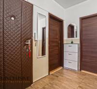 Előszoba fa dekoros padlóval, ruhásszekrénnyel és tükörrel egy háromszobás lakásban.