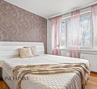 Hálószoba egy háromszobás lakásban dekoratív tapétával és fa mintázatú padlóval.