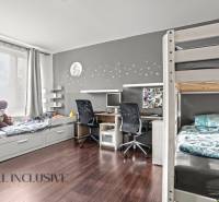 Gyerekszoba egy háromszobás lakásban emeletes ággyal, asztallal és fa dekorációjú padlóval.