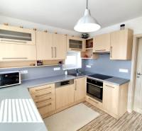 Konyha családi házban fa dekorációval és szürke munkalappal.