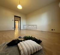 Szoba fa mintázatú padlóval egy háromszobás lakásban, világítás, világos színű falak.