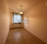 Keskeny világos helyiség ablakkal, függönyökkel és fa dekorációjú padlóval egy háromszobás lakásban.