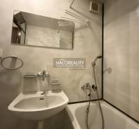 Fürdőszoba egy háromszobás lakásban káddal, tükörrel és fehér mosdóval.