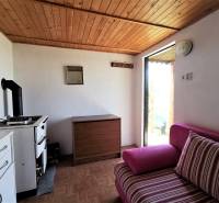 Egy hangulatos faházban van egy vintage tűzhely, fából készült mennyezet és kényelmes kárpitozott kanapé.