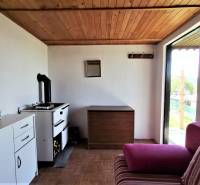 A konyhában van egy tűzhely, egy szekrény, egy rózsaszín kanapé és kilátás a kertre.