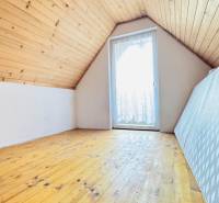 Padlásszoba a faházban fa mintázatú padlóval és tetőablakkal.