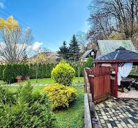 Kert a partizánskei háznál pavilonnal, gondozott bokrokkal és fákkal.