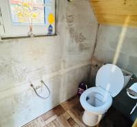 Fa házban lévő WC, fa dekoros padlóval és ablakkal.