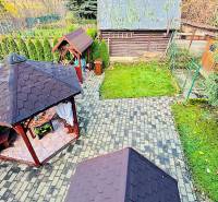 A Partizánskei ház körüli kerti pavilonokat zöld növényzet és kövezett sétányok veszik körül.