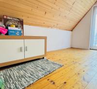 A fahatású padlóval rendelkező ház tetőtere, szekrénnyel és növénnyel.