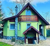 Ház Partizánskeban fa erkéllyel, zölddel körülvéve és kövezett udvarral.