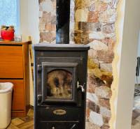 Kandalló kéménnyel, kőfal, fahatású padló egy faházban.