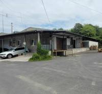 A Vasúti utcában a raktárak és csarnokok mellett áll egy épület autókkal és fával.