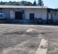 A Vasúti utcában raktárak és csarnokok találhatók, parkolóhelyekkel és autókkal.