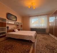 Hálószoba szőnyegekkel, ággyal, polcokkal és képpel egy családi házban.