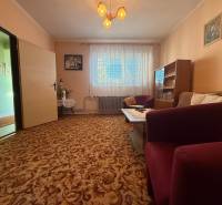 Nappali egy családi házban szőnyegpadlóval, bútorokkal és függönyökkel.