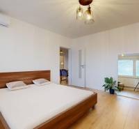 Hálószoba egy háromszobás lakásban ággyal, tükörrel és fa dekorációjú padlóval.