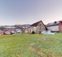 Családi ház Klenócon, zölddel körülvéve, havas tájjal a háttérben.