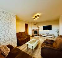 Nappali egy háromszobás lakásban, fa mintázatú padlóval és kényelmes ülőbútorokkal.