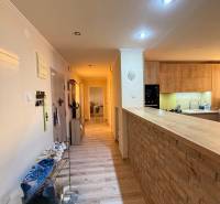 A fa dekorációjú padlóval ellátott folyosó egy háromszobás lakás konyhájába vezet.