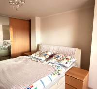 Hálószoba ággyal, beépített szekrénnyel és dekoratív csillárral egy háromszobás lakásban.