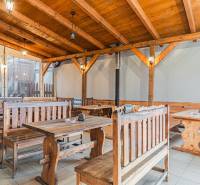 Egy szállodai és panziós stílusú étterem belső tere fa padokkal és asztalokkal.